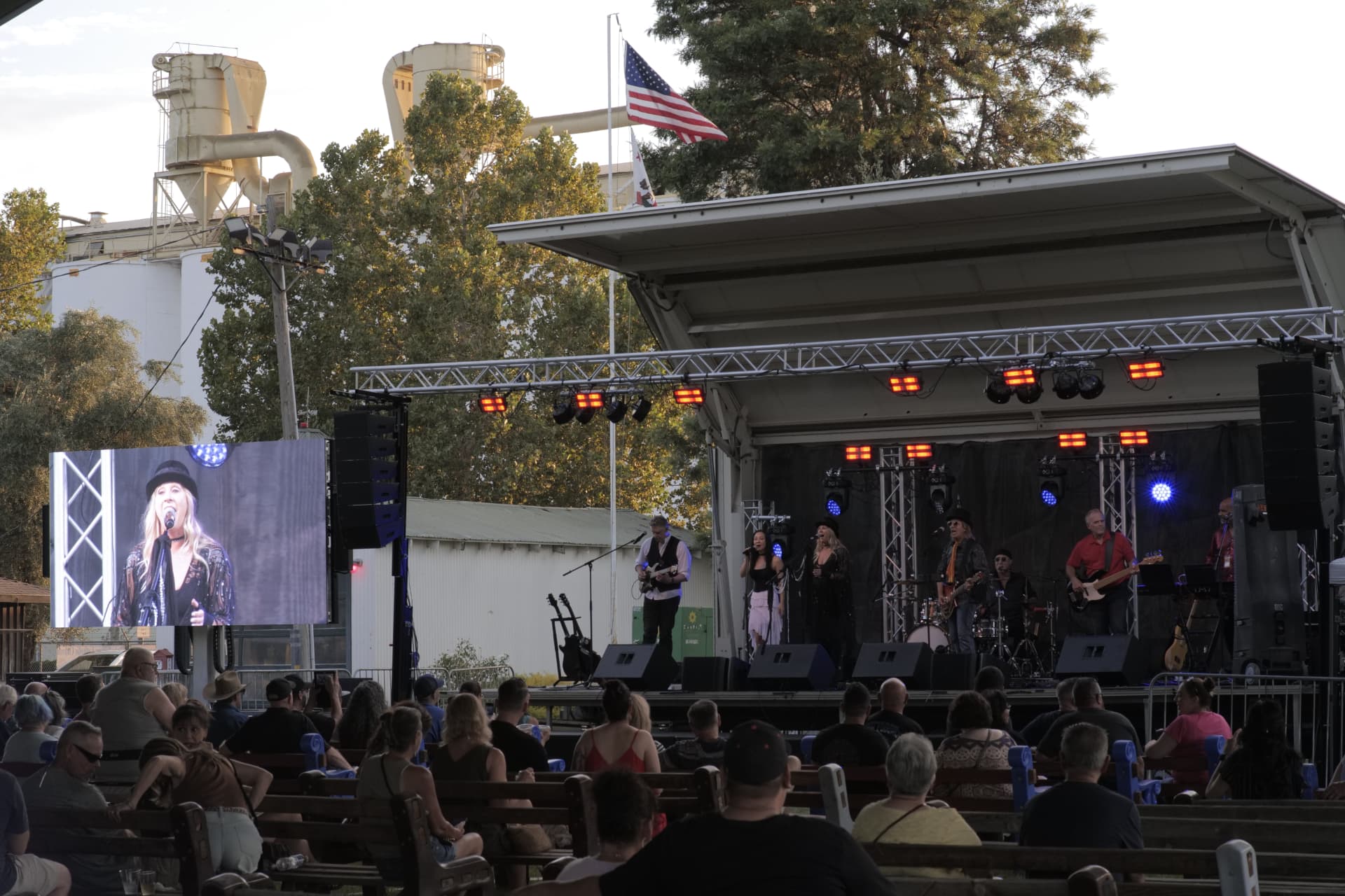 Festival main stage at dusk with a large crowd, line-array PA, stage lighting, and LED screen